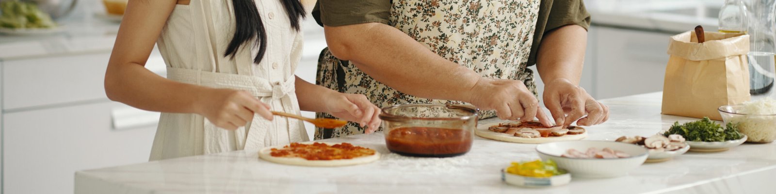 Mãos de Paciente de Priscilla Correia montando pizzas caseiras com ingredientes frescos.