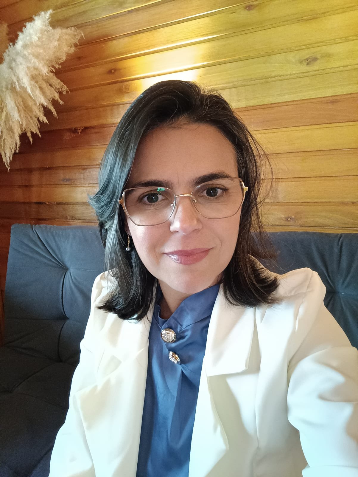 Priscilla Correia, nutricionista integrativa, usando óculos e blazer branco.